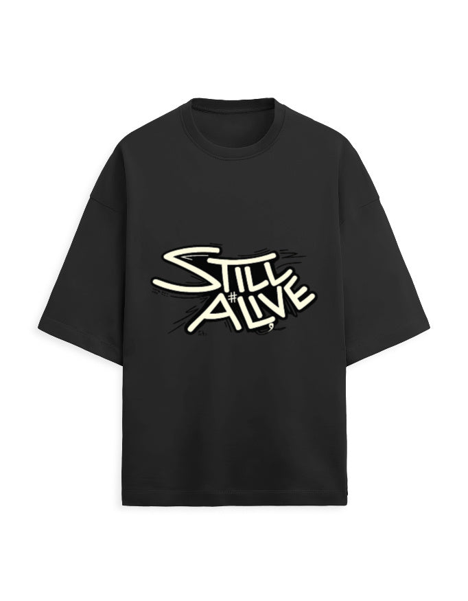 Black oversized terry tee with bold 'Still Alive' graffiti-style typography chest print