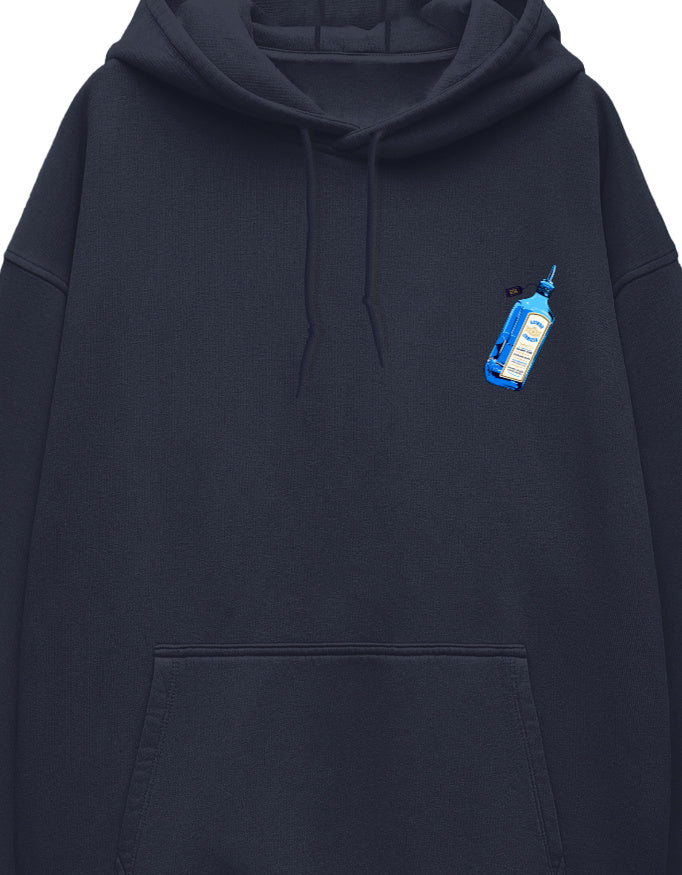 Small illustrated blue glass bottle graphic with a cream label printed on the left chest of a white unisex oversized hoodie.